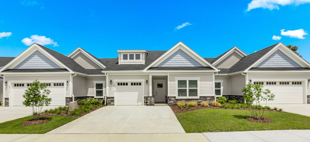 a white house with white garage doors and a driveway