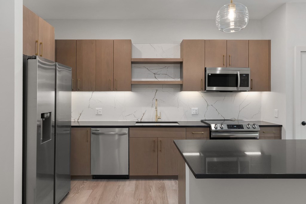 A modern kitchen with a stainless steel refrigerator, microwave, and oven.
