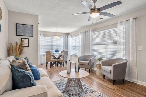 A living room with a beige sofa, a coffee table, and a ceiling fan.