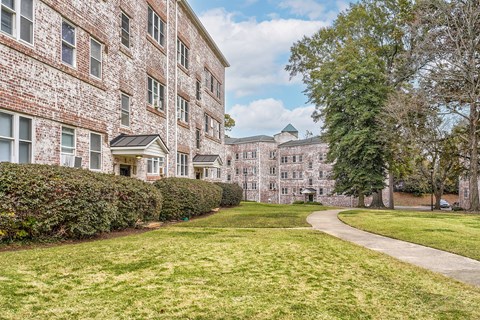 A large brick building with a green lawn in front.