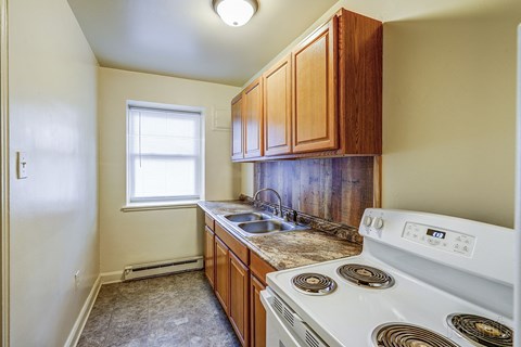 A small kitchen with a white stove and wooden cabinets.