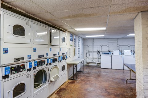 A laundromat with a row of washers and dryers.