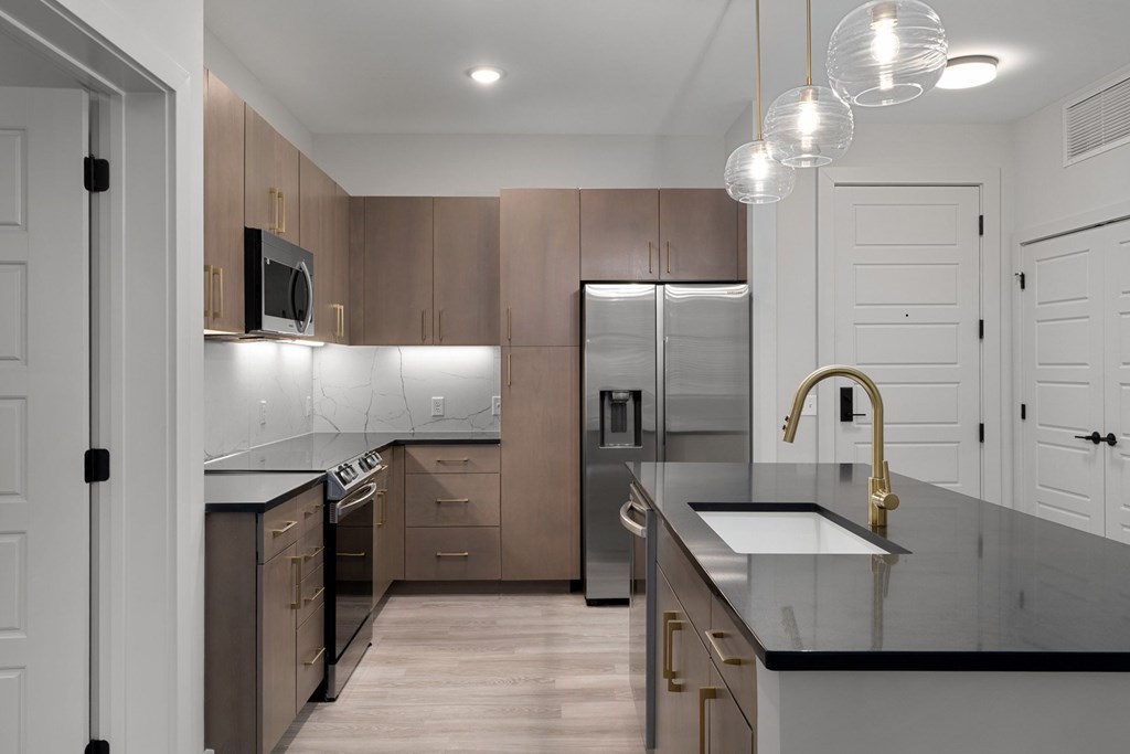 A modern kitchen with a black countertop and stainless steel appliances.