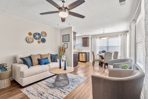A living room with a white couch, a coffee table, and a ceiling fan.