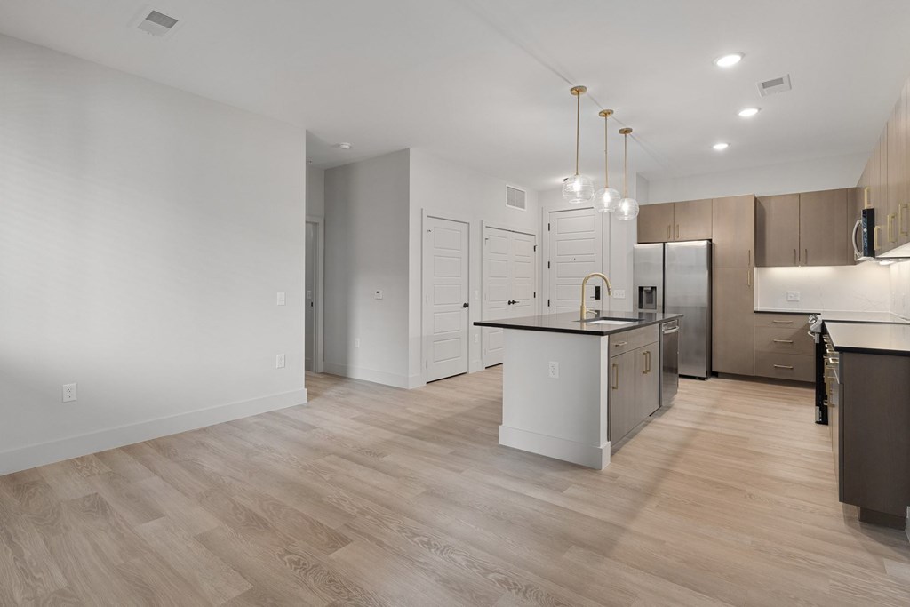 A modern kitchen with a white island and wooden flooring.