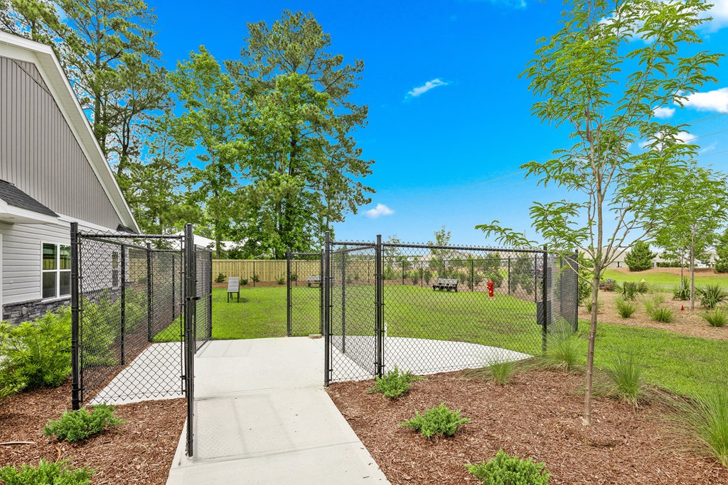a fenced in yard with trees and a sidewalk