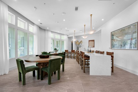 a large dining room with a long table and chairs and a kitchen with large windows a large dining room with a long table and chairs and a kitchen with large windows at The Enclave at Deer Moss Creek, Florida