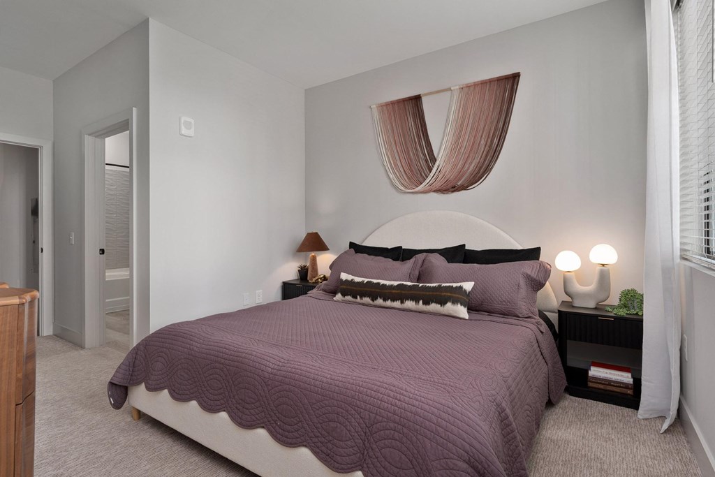 A bedroom with a large bed and a wooden dresser.