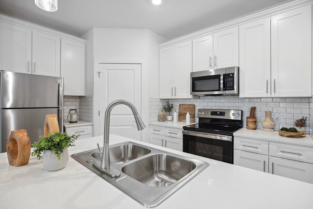 a white kitchen with stainless steel appliances and a sink