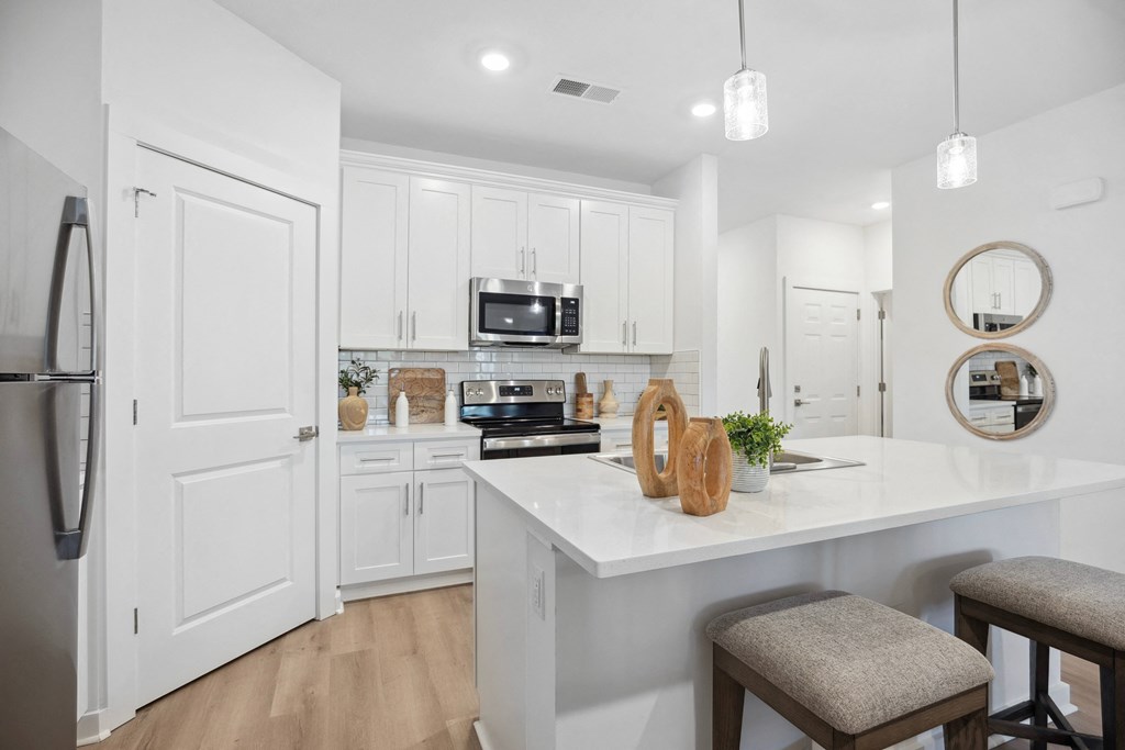 an open kitchen and dining area with white cabinets and a white counter top