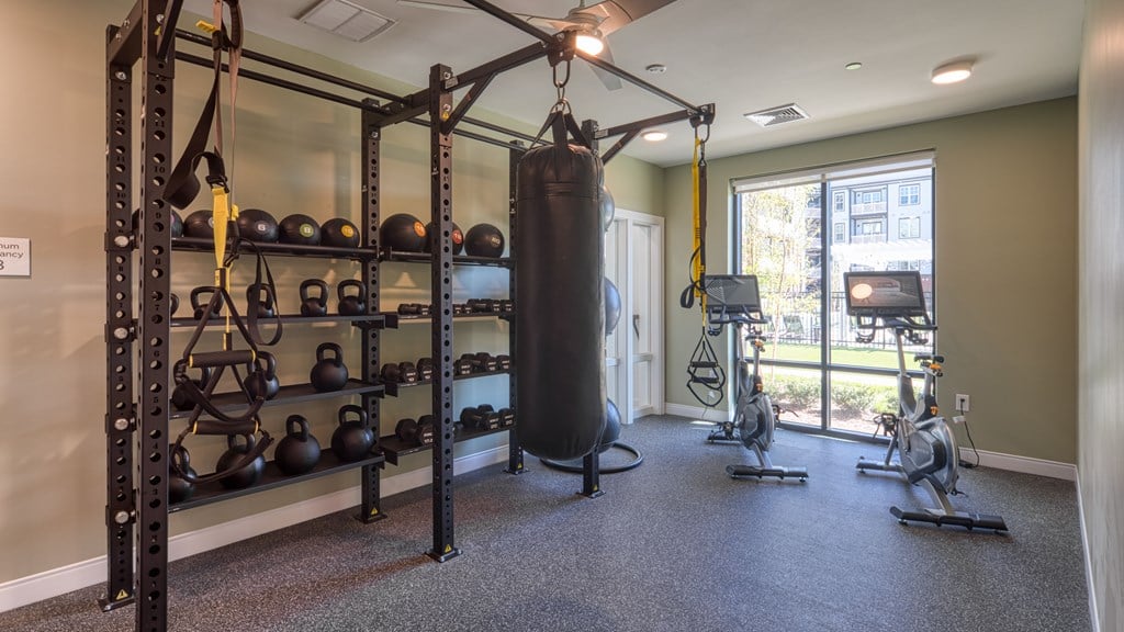 A gym with a punching bag, weights, and exercise bikes.