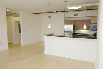 an empty living room with a kitchen and a counter top