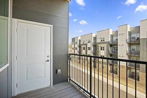 A white door is on the left of a balcony with a black railing.