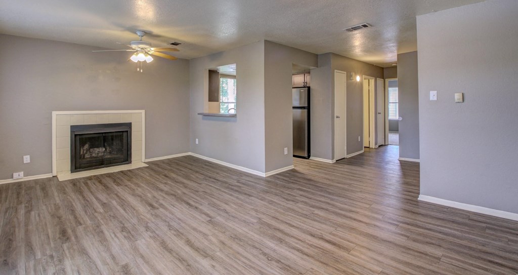 an empty living room with a fireplace and a ceiling fan