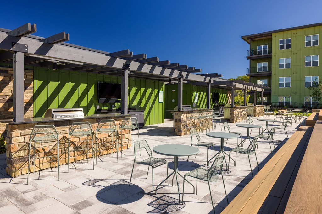 A patio with tables and chairs is covered by a roof.
