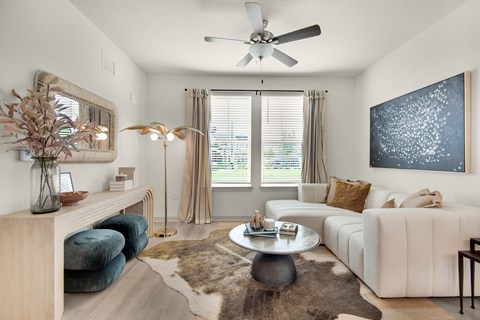 A living room with a white couch, a coffee table, and a large painting on the wall.