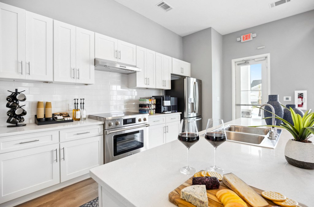 a kitchen with white cabinets and a table with two glasses of wine