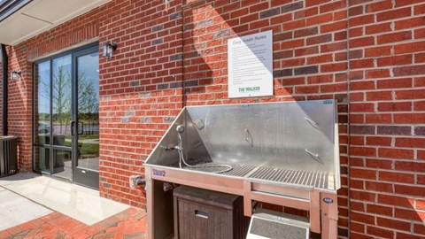 A metal grill is attached to a brick wall outside a building.