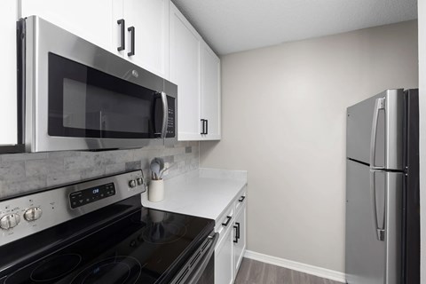 A modern kitchen with a black stove top oven and a black microwave above it.