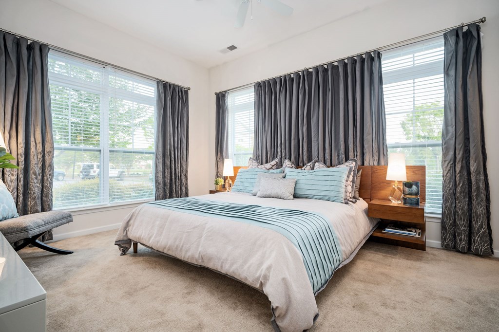 A bedroom with a large bed and a window with curtains.