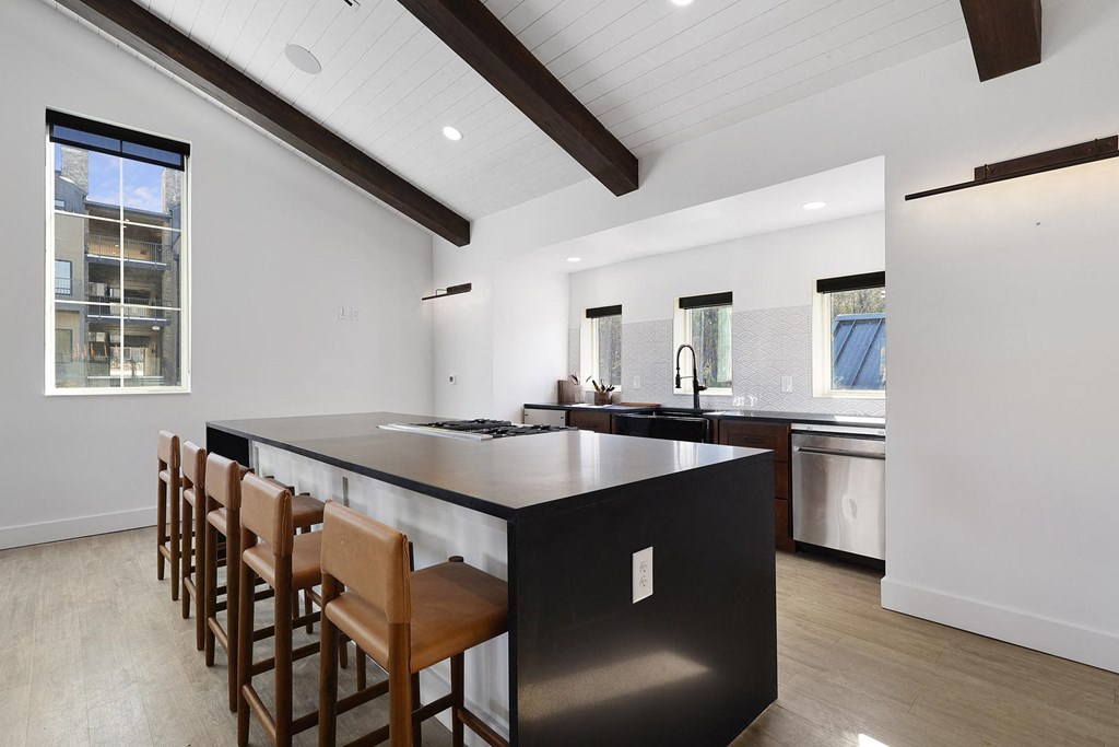 A modern kitchen with a black countertop and wooden bar stools. at Terraces at High Mountain, Alabama, 35811