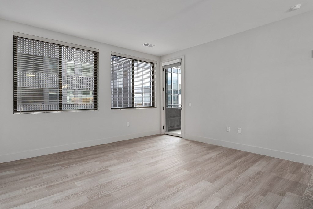 A room with a wooden floor and a door leading to a balcony.