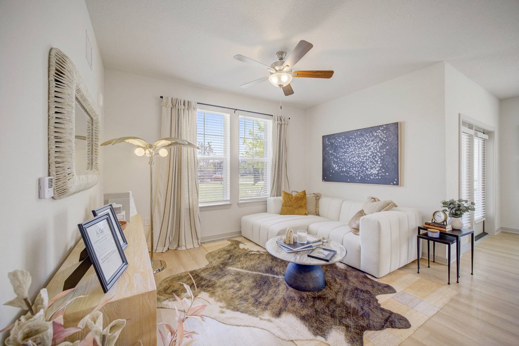 A living room with a white couch, a rug, and a painting on the wall.