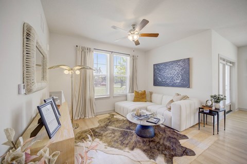 A living room with a white couch, a rug, and a painting on the wall.