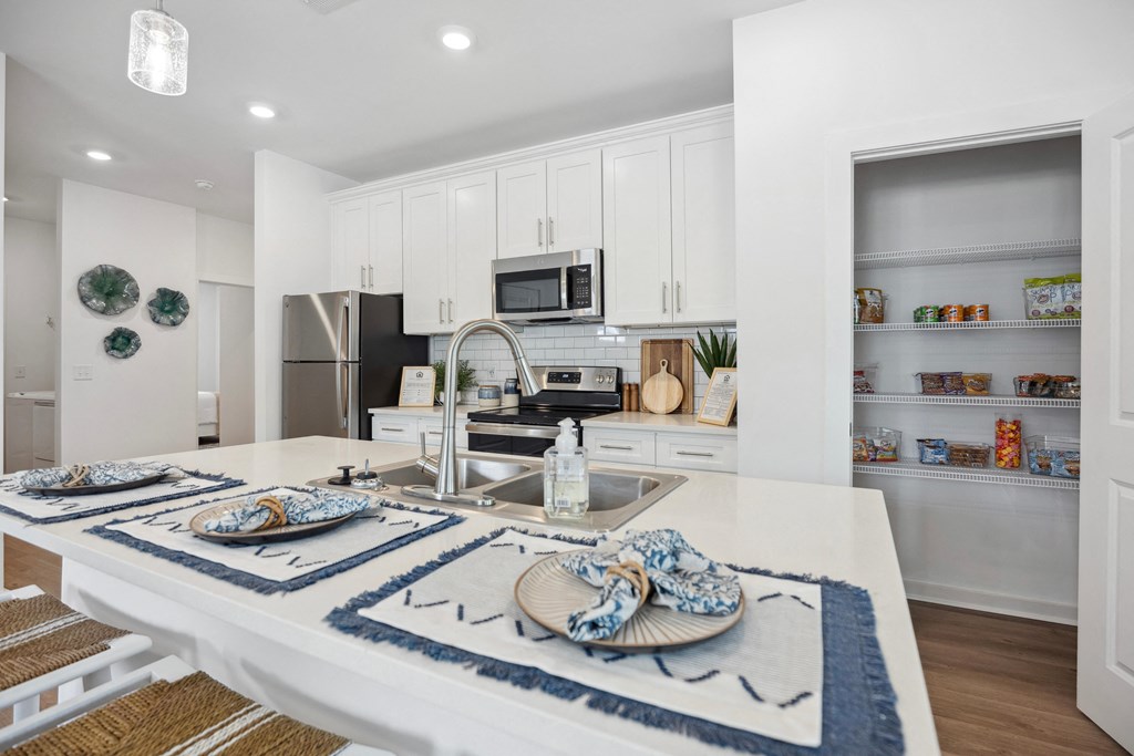an open kitchen and dining area with white cabinets and stainless steel appliances