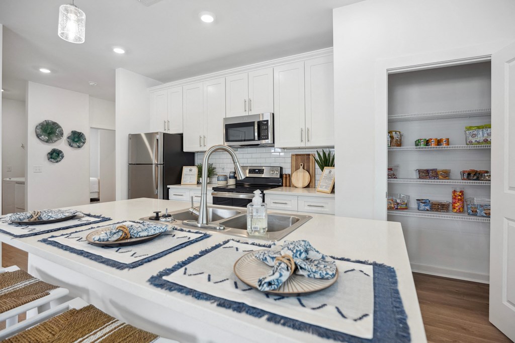 an open kitchen and dining area with white cabinets and stainless steel appliances