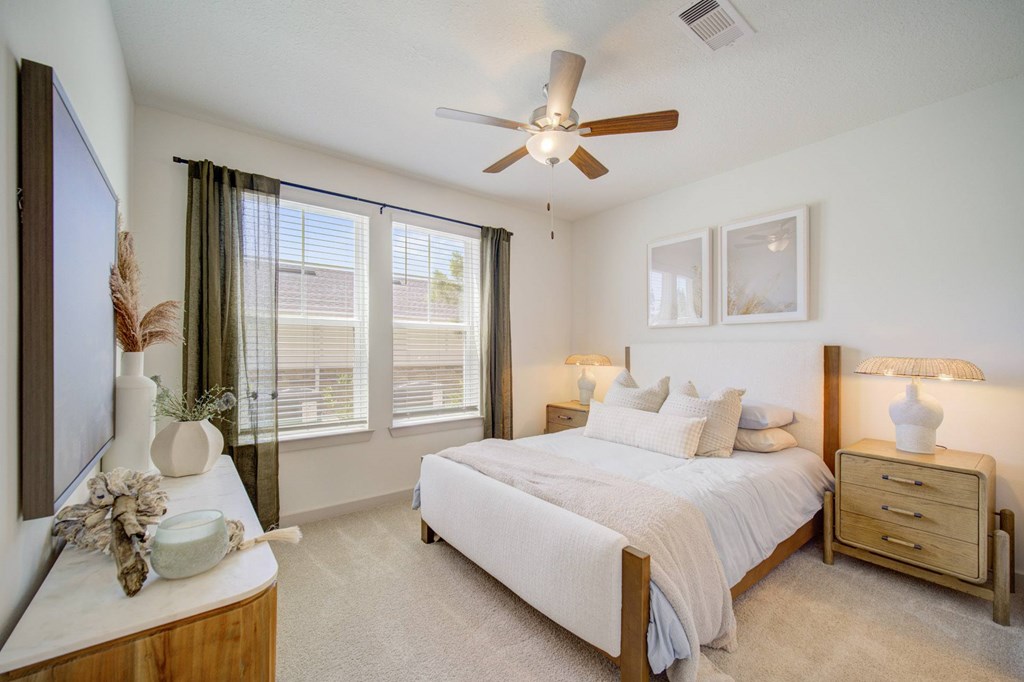 A bedroom with a bed, nightstand, and a ceiling fan.