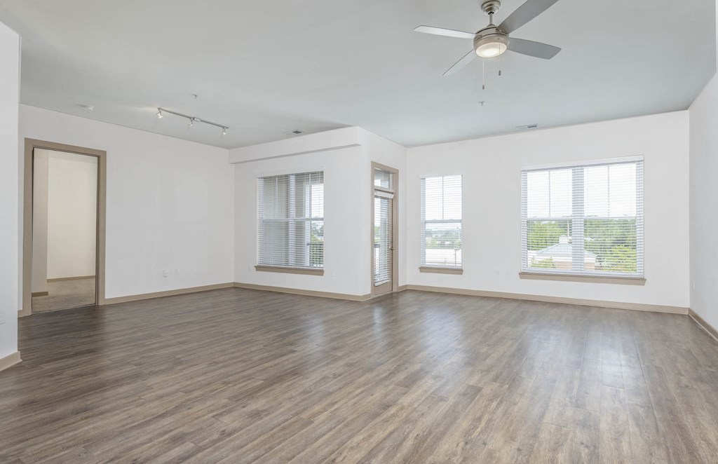 an empty living room with wood floors and a ceiling fan