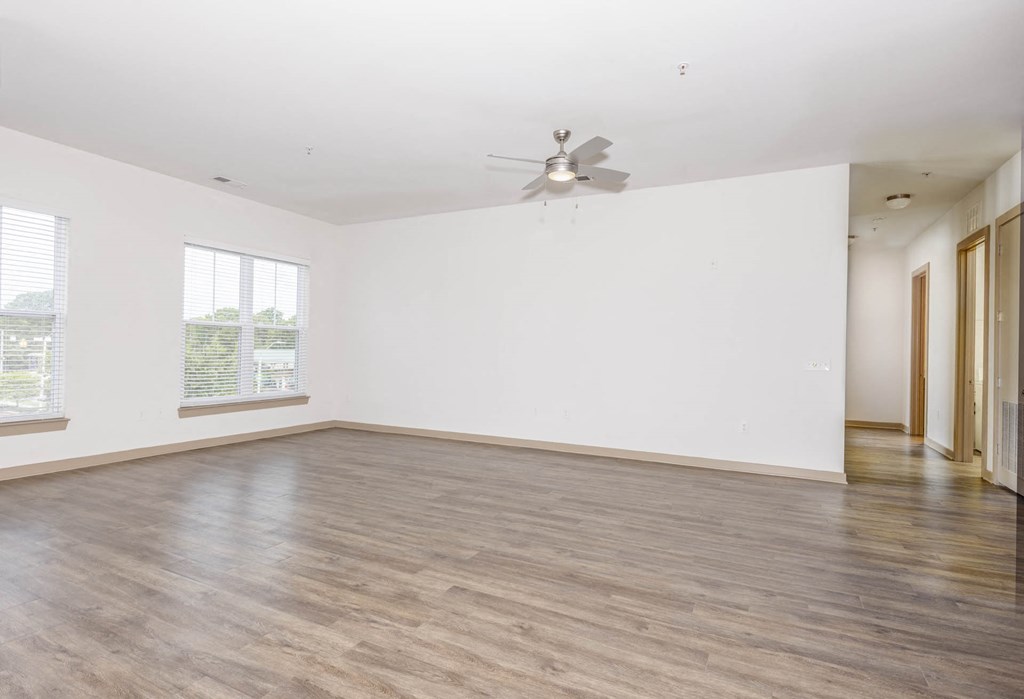 an empty living room with white walls and a ceiling fan