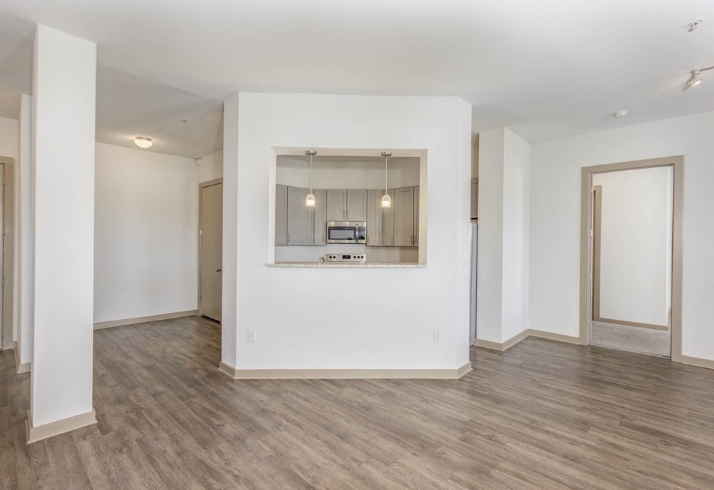 a living room and kitchen with white walls and wood floors