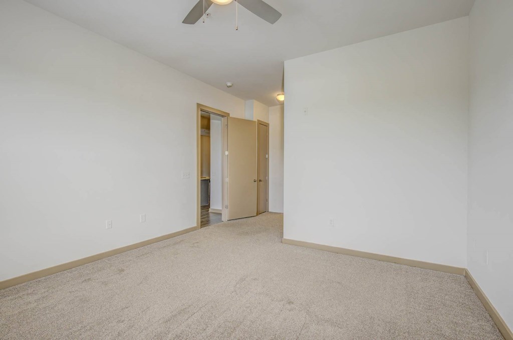 a living room with white walls and a ceiling fan
