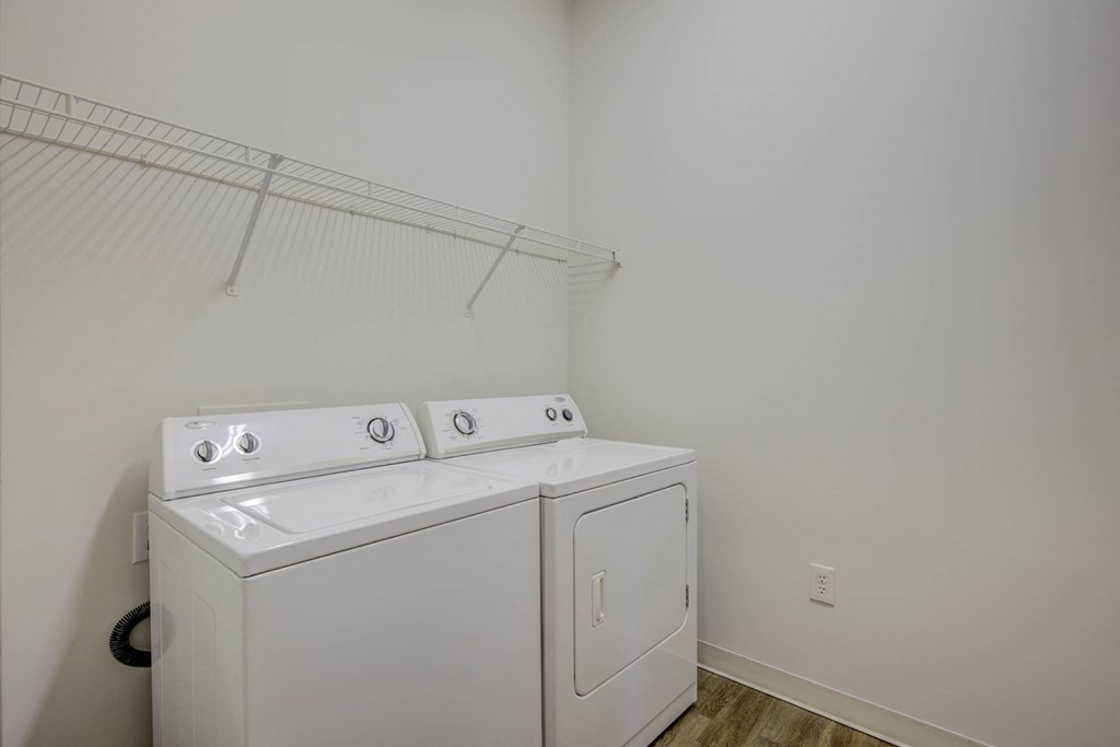 a washer and dryer in a white room with a rack on the wall