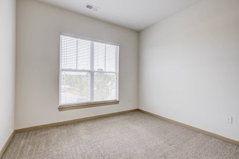 a bedroom with a large window and a carpeted floor