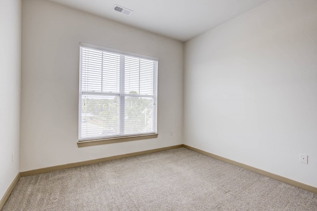a bedroom with a large window and a carpeted floor