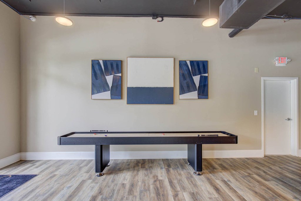 a games room with a pool table and paintings on the wall