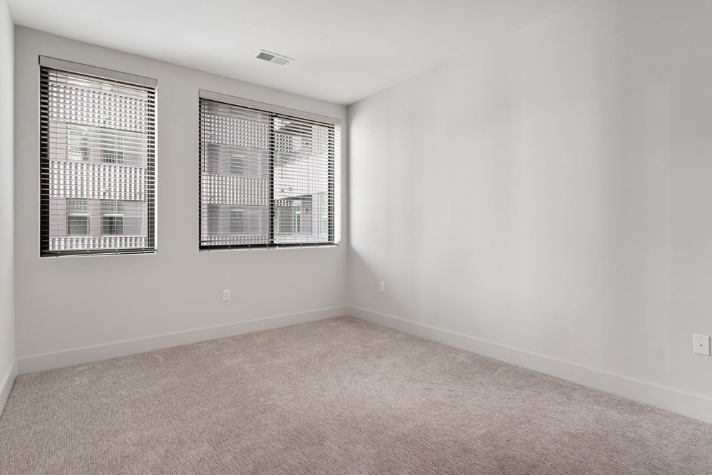A room with two windows and carpeted floor.