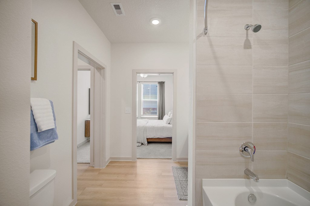 A bathroom with a white tub and a window.
