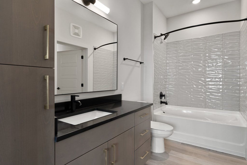 A modern bathroom with a white tub, sink, and a large mirror.
