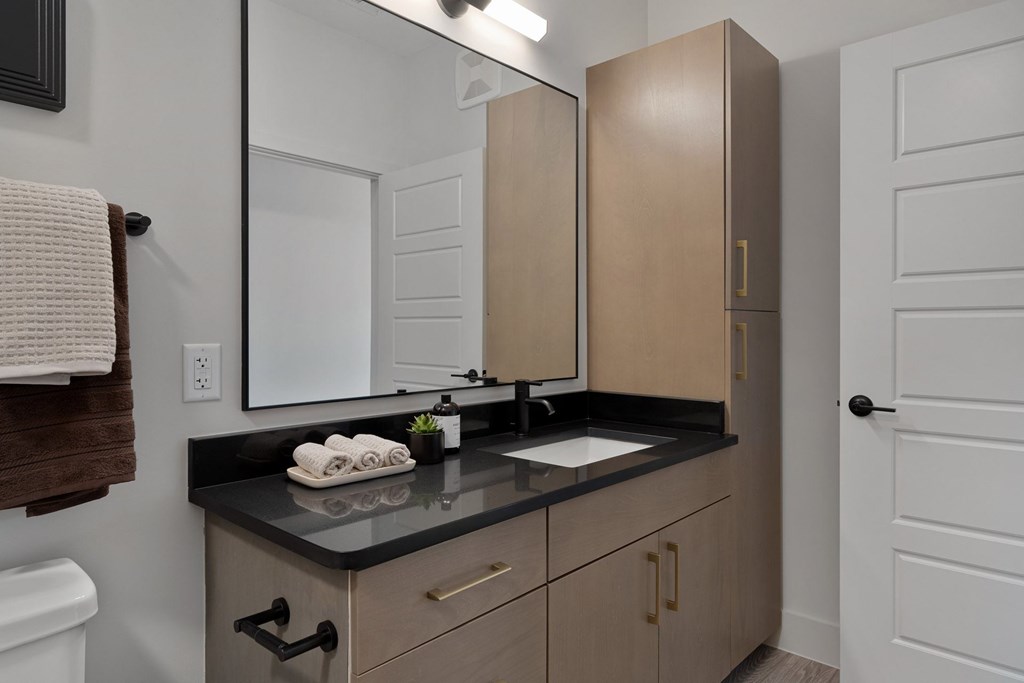 A bathroom with a sink, mirror, and cabinets.