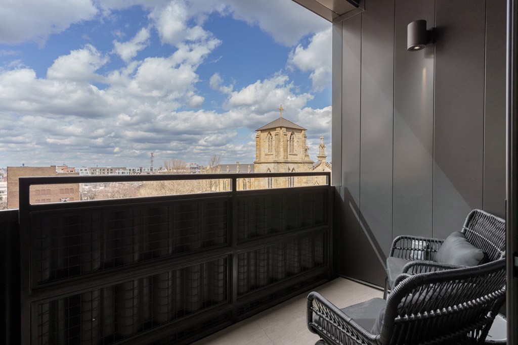 A balcony with a chair and a table with a view of a building in the distance.
