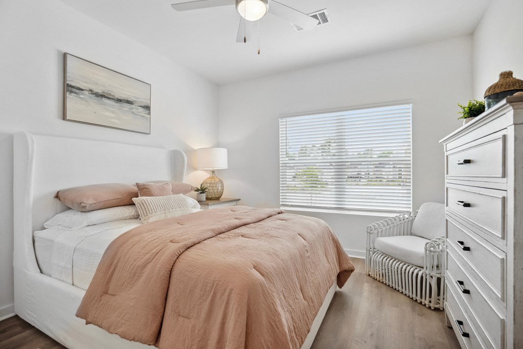 a bedroom with white furniture and a bed with peach bedding