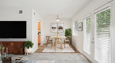 A living room with a television, a dining table, and chairs.