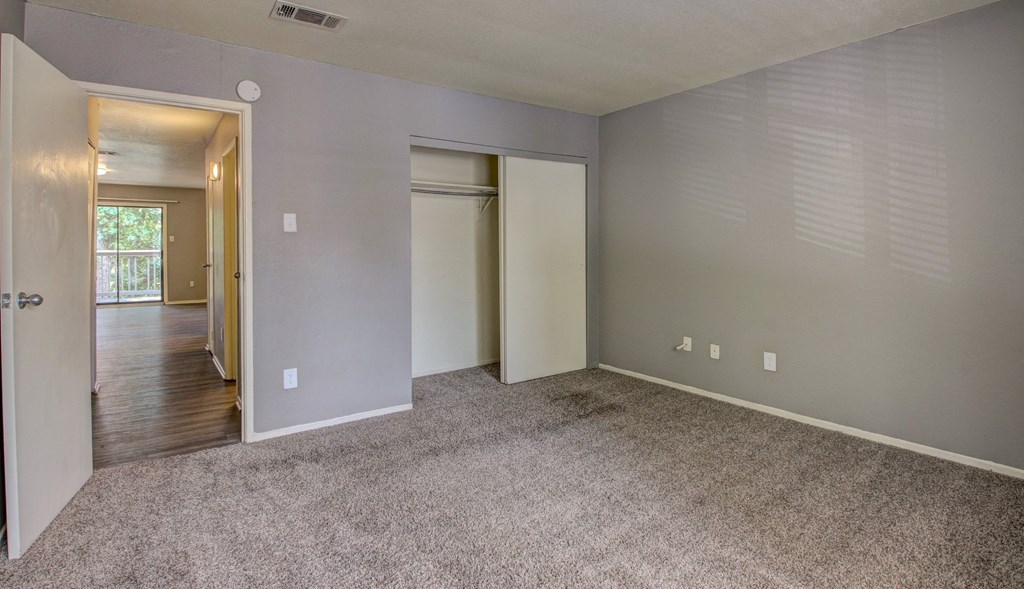 an empty living room with carpet and a door to a hallway