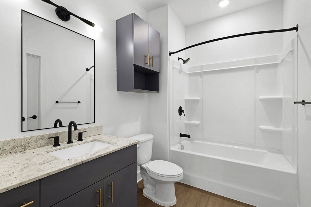 A white toilet sits next to a sink in a bathroom.at Boardwalk at Research Park, Huntsville, AL 35806
