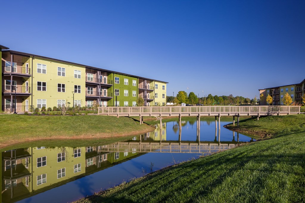 A bridge crosses a body of water in front of apartment buildings.