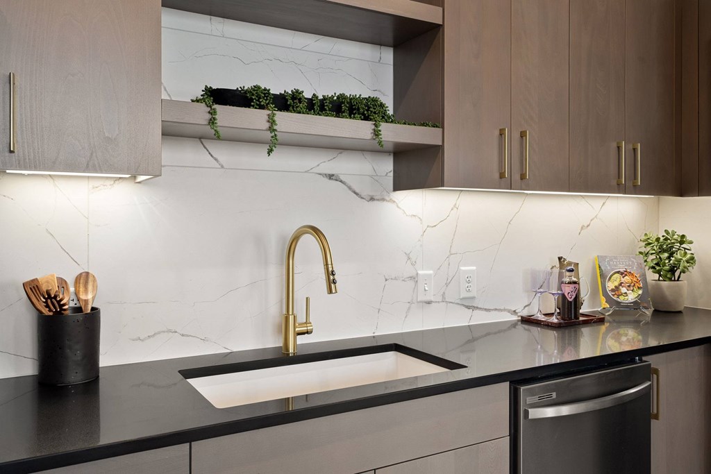 A modern kitchen with a marble backsplash and a black countertop.